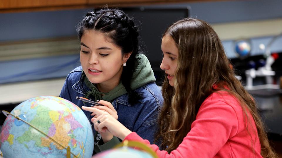 两个学生在地球科学课上研究地球仪